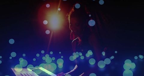 Backlit Performer Playing Synth on Dim Stage with Bokeh Spotlight and Moody Silhouette