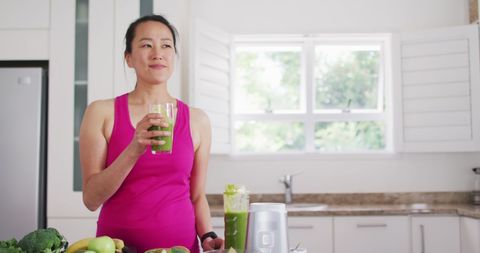 Smiling Woman in Kitchen Enjoys Healthy Green Smoothie - Download Free Stock Images Pikwizard.com