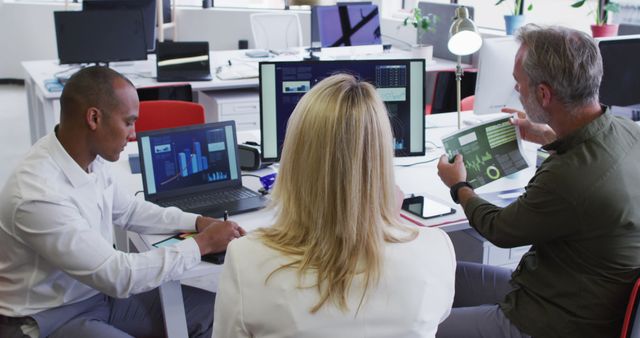 Diverse business people sitting using computer and takling at desk in office - Download Free Stock Photos Pikwizard.com