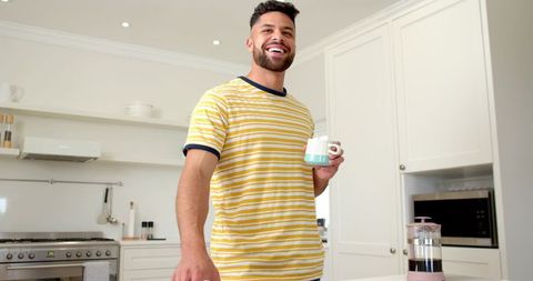 Cheerful Man Enjoying Coffee in Modern Minimalist Kitchen