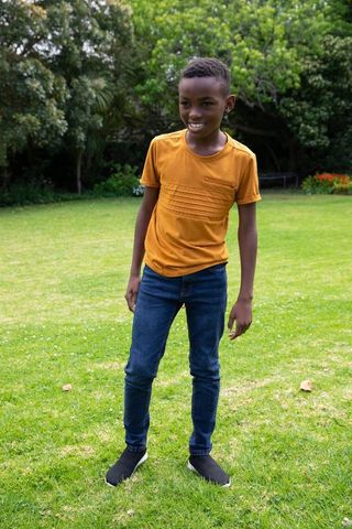 Smiling boy in yellow tee enjoying garden