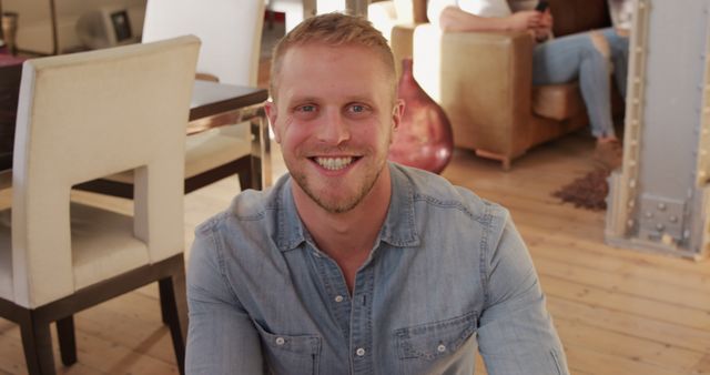 Smiling Man in Denim Shirt Sitting in Bright Living Room - Download Free Stock Images Pikwizard.com