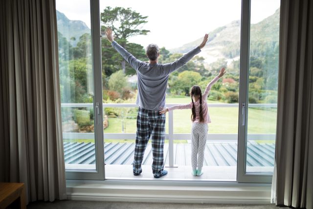 Father and daughter stretching on balcony in the morning, enjoying the fresh air and scenic view. Ideal for use in family, lifestyle, and wellness content, emphasizing relaxation, bonding, and morning routines.