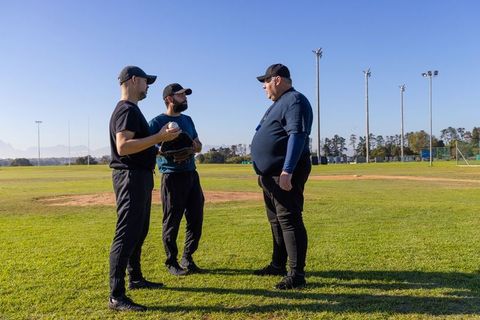 Baseball Coach Advising Two Players on Infield Positioning During Practice