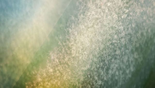 Shimmering backlit fountain spray forming luminous diagonal column with soft bokeh glow