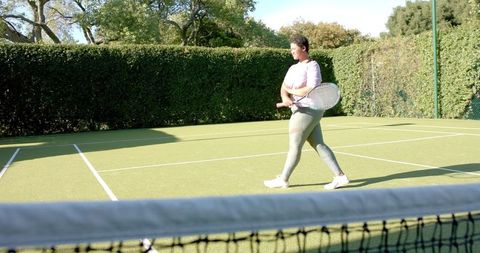 Woman Enjoying Tennis Game Outside on Sunny Day