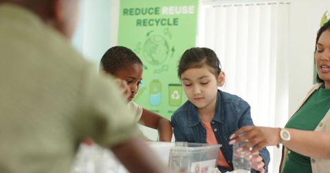 Teacher guiding diverse kids sorting recycling in classroom for sustainability education