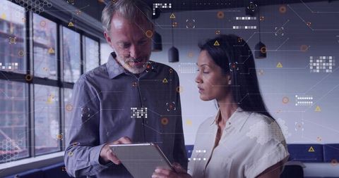Tech professionals reviewing data on tablet with augmented reality overlay in office