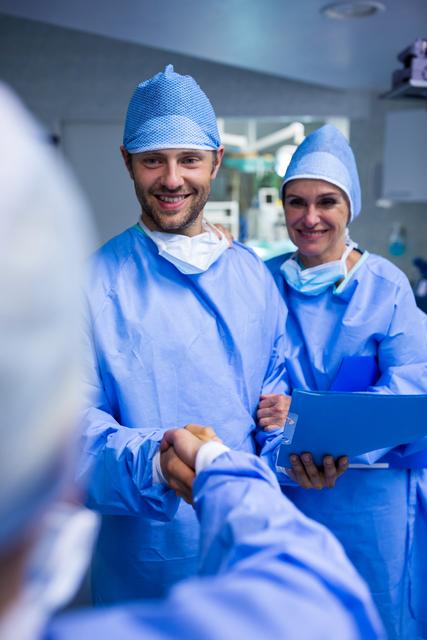 Surgeons shaking hand in operation room at hospital