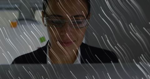 Businesswoman analyzing laptop data through rain-effect glass with sticky notes