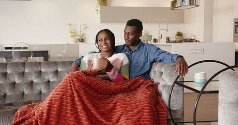 Happy Couple Relaxing on a Cozy Couch at Home with Drinks