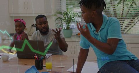 Father and Son Collaborating on Homework at Kitchen Table with Laptop and Data Graph