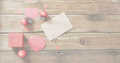 Displaying valentine flatlay with blank card, pink hearts and gift box on rustic wood