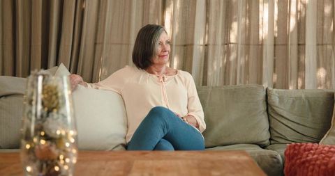 Senior woman relaxing on cozy sectional sofa in warm living room