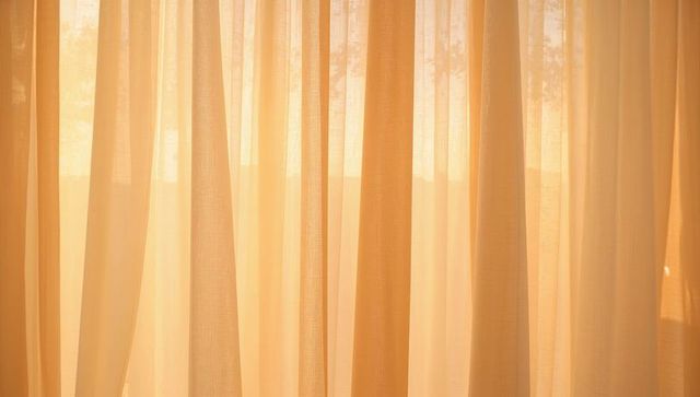 Filtering sheer beige curtains softening sunlight revealing faint tree silhouettes