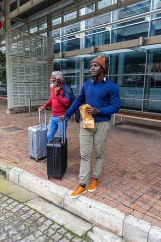 African american travelers walking with luggage at urban transit hub