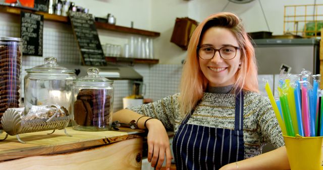 Smiling Female Barista in Cozy Café with Jars of Cookies and Colorful Straws - Download Free Stock Images Pikwizard.com