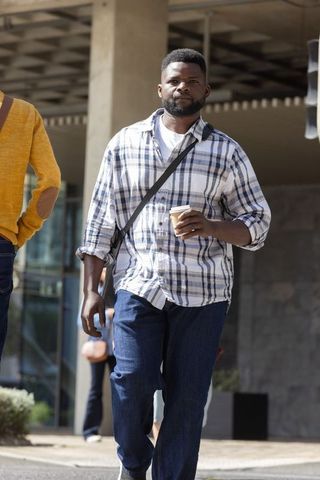 Two african men walking with coffee at urban plaza wearing casual plaid and crossbody bags