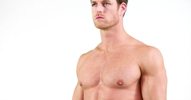A shirtless Caucasian young man appears focused and serious, with copy space. His physique suggests he might be an athlete or fitness enthusiast.