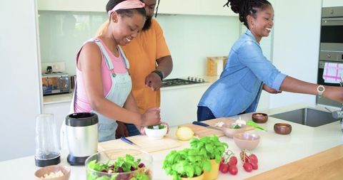 African american family preparing healthy meal in bright kitchen with mortar and pestle