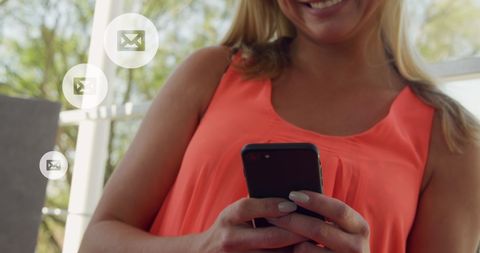 Smiling Woman Reading Messages on Smartphone Outdoors