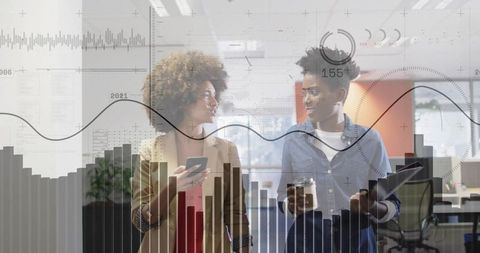 Walking colleagues in modern workspace with smartphone, tablet and data overlay charts