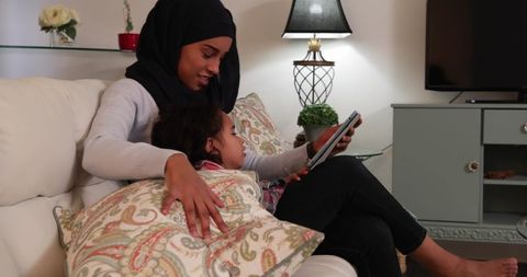 Young Mother and Daughter Enjoying Tablet Time on Sofa