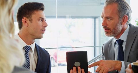 Business Meeting Discussion Over Tablet in Modern Cafe Setting