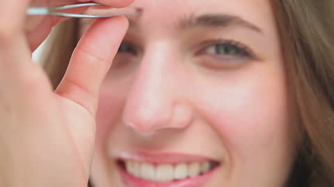 Cheerful Woman Tweezing Eyebrows Up Close