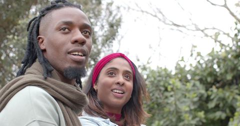 Multicultural Couple Looking Up in Park Smiling and Observing Nature on Overcast Day