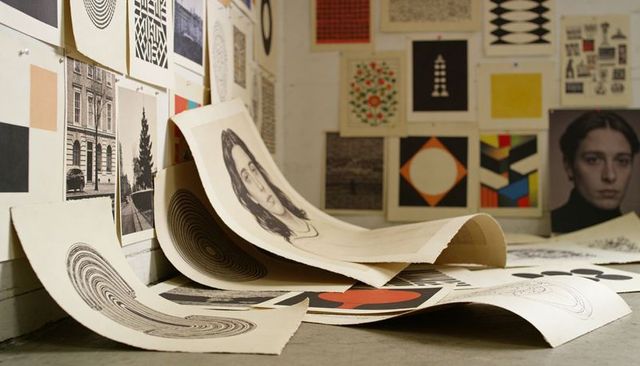 Curled charcoal portrait prints studio corner featuring geometric prints and rolled papers