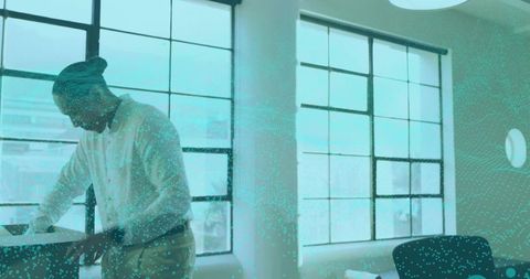 Professional reviewing documents in modern sunlit office with teal data particle overlay