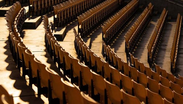 Curved wooden stadium seats casting long shadows at golden hour