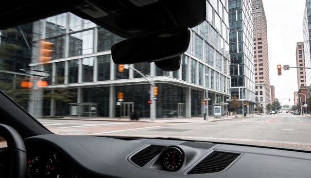 Driver pov through windshield at urban intersection with modern glass office towers