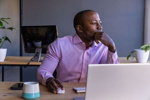 Thoughtful Professional Gazing at Laptop in Modern Office