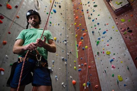 Male Climber Manages Rope on Indoor Climbing Wall for Training