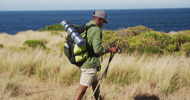 Hiker walking along a coastal trail, carrying a backpack equipped with camping gear. Ideal for illustrating concepts of outdoor adventure, nature exploration, trekking, and travel. Useful for promoting hiking gear, outdoor activities, nature tourism, and fitness.