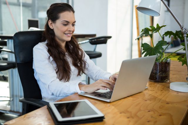 Female business executive using laptop in office