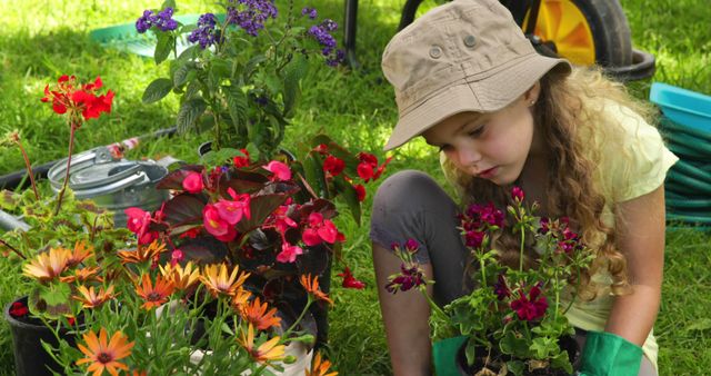 Young girl with curly hair and casual hat is engaging in gardening tasks, surrounded by colorful flowers in a sunny yard. This image is perfect for content related to outdoor activities, children's hobbies, gardening tips, springtime activities, and family bonding.