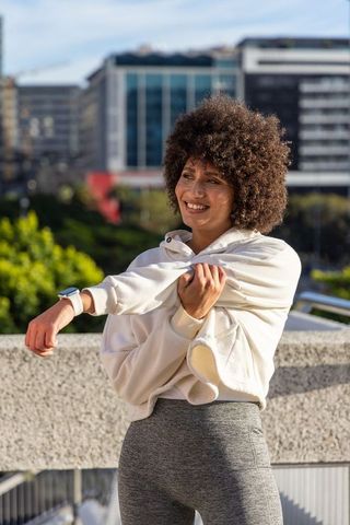 African american woman stretching before workout on urban terrace with skyline view