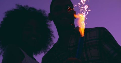 Young Couple with Sparklers Celebrating at Dusk on Beach