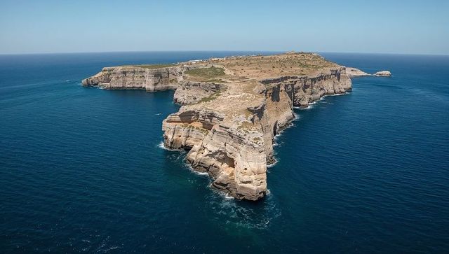 Aerial panorama of stratified cliff headland stretching into open ocean with footpaths