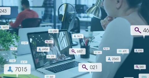 Woman working at laptop in open-plan office with analytics overlays and collaboration