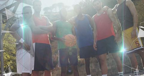 Young men posing on sunlit outdoor basketball court holding ball with lens flare energy