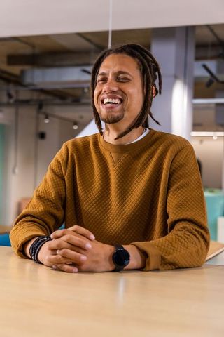 Laughing professional in mustard sweatshirt at coworking space, candid portrait