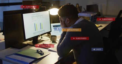 Leaning analyst analyzing dual-monitor dashboards with notification overlays in late-night office
