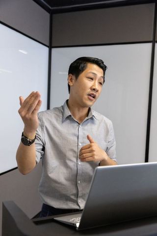 Asian professional delivering presentation in modern meeting room