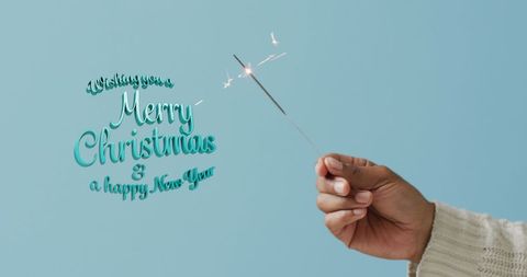 Hand Holding Sparkler with Christmas Greetings on Blue Background