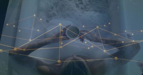 Relaxing woman holding mug in bubble bath with golden network overlay