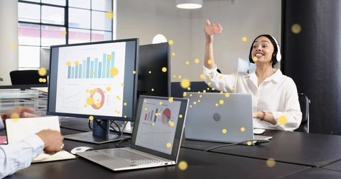 Female leader presenting with headset in modern open office showing data charts on screens